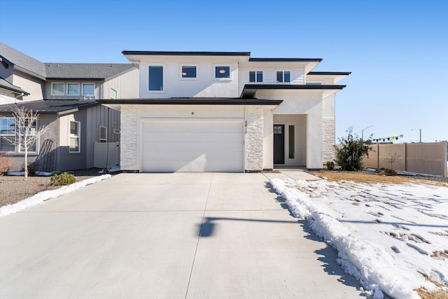 view of front of property with stucco siding, concrete driveway, fence, a garage, and stone siding