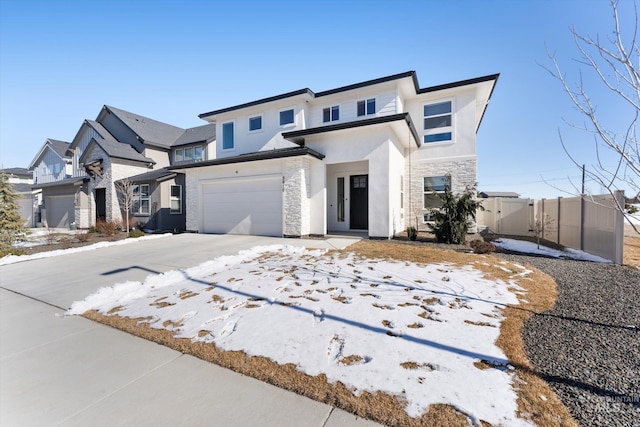 view of front of house featuring an attached garage, fence, stone siding, concrete driveway, and stucco siding