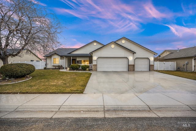 view of front of house with driveway, a garage, fence, and a yard