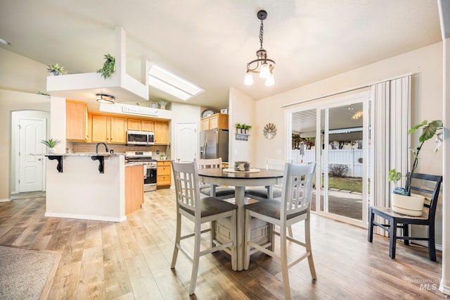 dining area featuring light wood-type flooring and vaulted ceiling