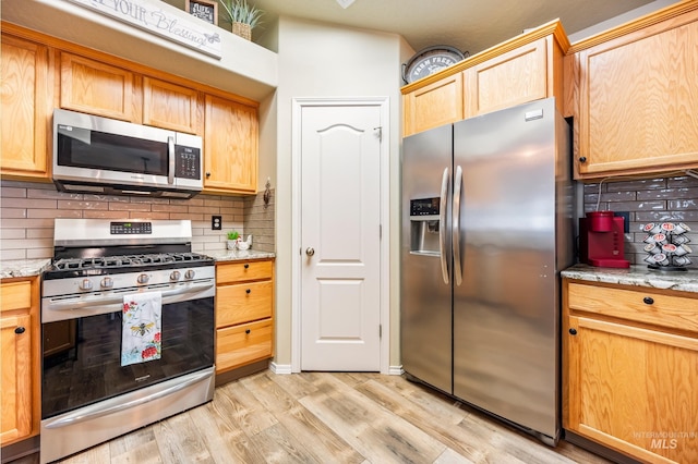 kitchen featuring light wood-style floors, stainless steel appliances, decorative backsplash, and light brown cabinetry