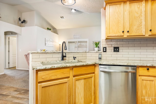 kitchen featuring visible vents, backsplash, a peninsula, stainless steel dishwasher, and a sink