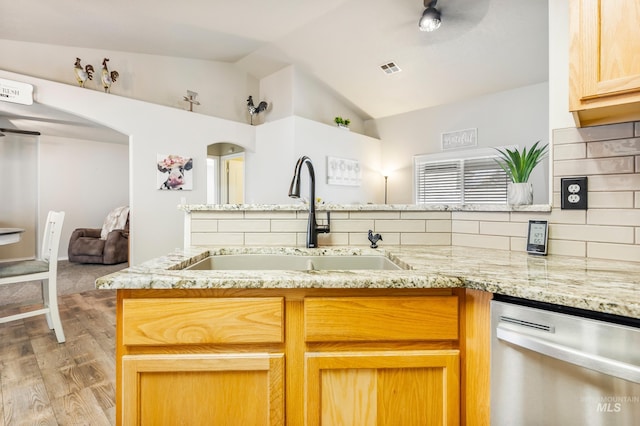 kitchen featuring dishwasher, light stone counters, a sink, and lofted ceiling