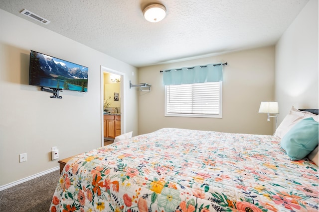 carpeted bedroom featuring a textured ceiling, connected bathroom, visible vents, and baseboards