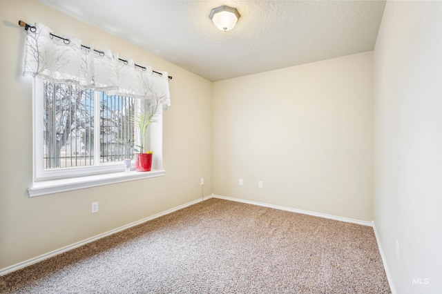 carpeted empty room with a textured ceiling and baseboards