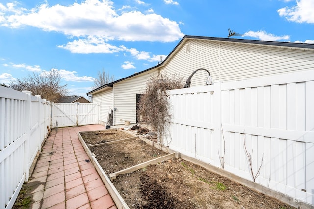 view of side of home with a fenced backyard and a vegetable garden