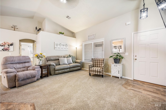 carpeted living room with visible vents, arched walkways, baseboards, wood finished floors, and high vaulted ceiling