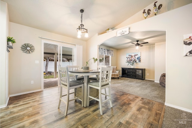 dining space with baseboards, arched walkways, lofted ceiling, ceiling fan, and wood finished floors