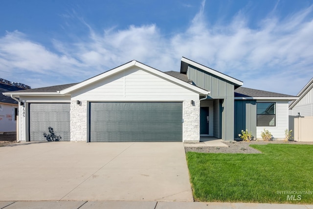 view of front facade featuring board and batten siding, a front yard, concrete driveway, and an attached garage