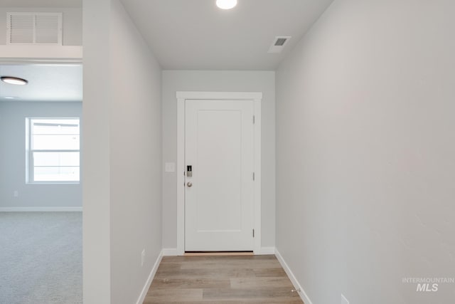 doorway to outside with baseboards, visible vents, and light wood-style flooring