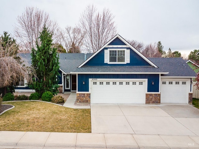 view of front of property with a front lawn, an attached garage, stone siding, and driveway