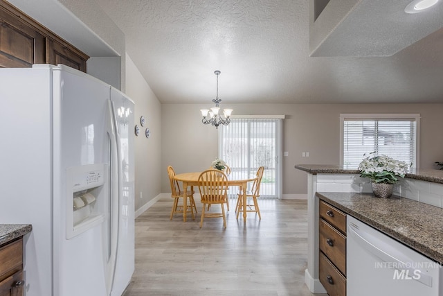 kitchen featuring white appliances, plenty of natural light, light wood-type flooring, and a chandelier