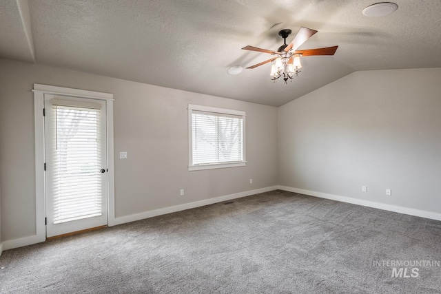 spare room with a textured ceiling, carpet flooring, baseboards, ceiling fan, and vaulted ceiling