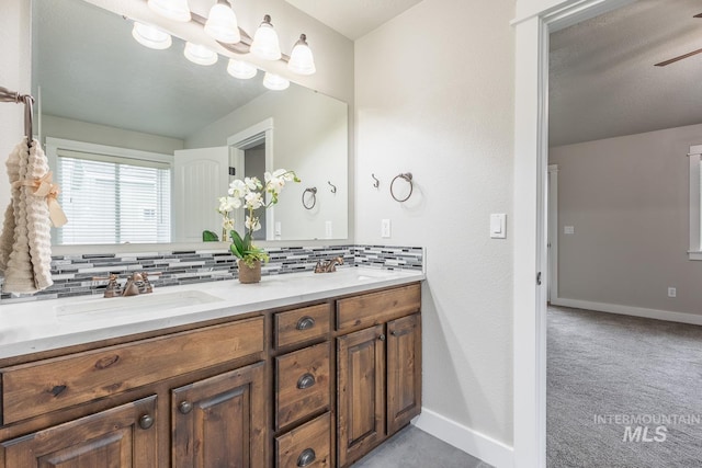 bathroom featuring a ceiling fan, baseboards, double vanity, a sink, and backsplash