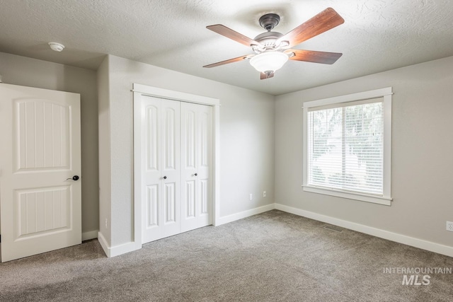 unfurnished bedroom featuring a closet, baseboards, a textured ceiling, and carpet flooring