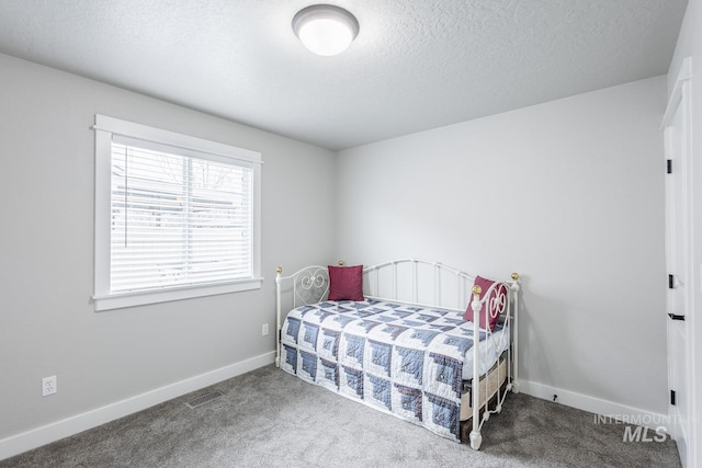 carpeted bedroom with visible vents, baseboards, and a textured ceiling