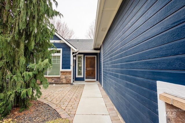 view of exterior entry featuring stone siding and a patio