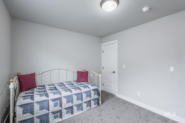 bedroom featuring carpet flooring, baseboards, and a textured ceiling