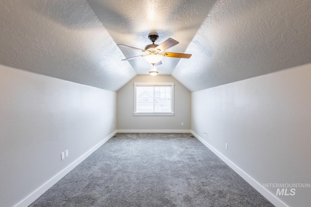 additional living space with a ceiling fan, a textured ceiling, carpet flooring, baseboards, and vaulted ceiling