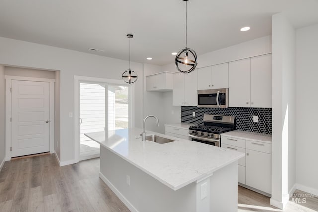 kitchen featuring white cabinetry, sink, hanging light fixtures, a kitchen island with sink, and appliances with stainless steel finishes