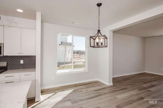 unfurnished dining area featuring a chandelier and light hardwood / wood-style flooring