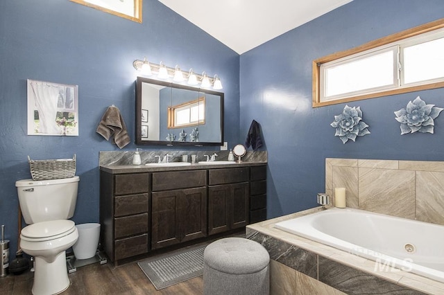 full bath featuring vanity, toilet, wood finished floors, lofted ceiling, and a jetted tub