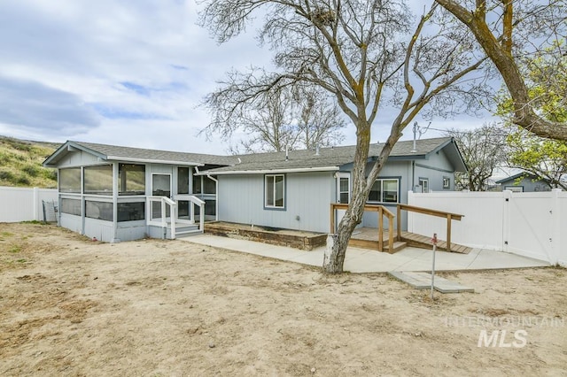 rear view of property with a sunroom, a patio, fence, and a gate