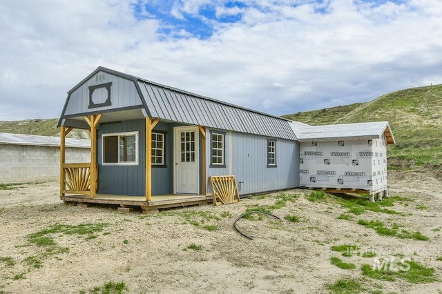back of property featuring an outdoor structure and metal roof
