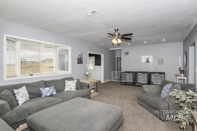 carpeted living area featuring visible vents and a ceiling fan
