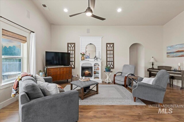 living room with wood finished floors, visible vents, and a lit fireplace