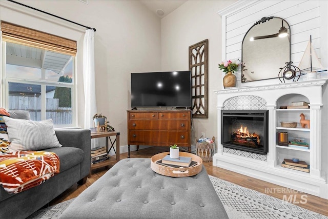 living room with a glass covered fireplace, baseboards, and wood finished floors