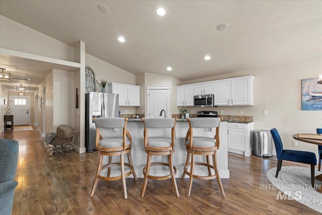 kitchen featuring white cabinets, an island with sink, dark wood-style floors, and appliances with stainless steel finishes