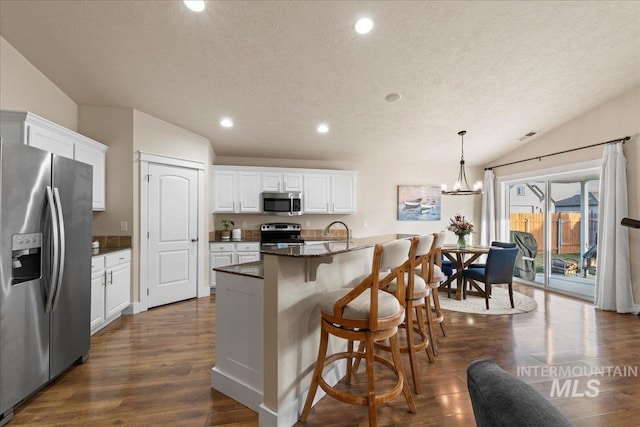 kitchen featuring stainless steel appliances, lofted ceiling, dark wood-type flooring, and white cabinets