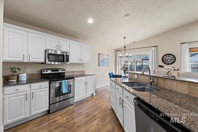 kitchen with a sink, stainless steel appliances, white cabinetry, and vaulted ceiling