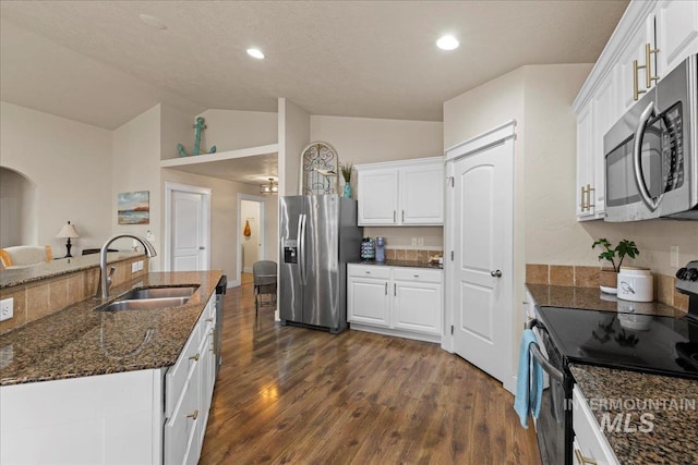 kitchen featuring dark wood-type flooring, a sink, stainless steel appliances, dark stone counters, and white cabinets