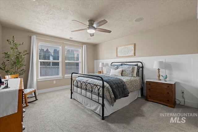 bedroom featuring light carpet, baseboards, a textured ceiling, and ceiling fan