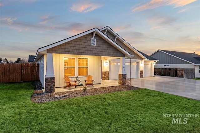 craftsman-style home featuring concrete driveway, fence, and a front yard