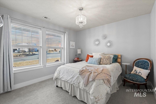 carpeted bedroom with baseboards, visible vents, a chandelier, and a textured ceiling