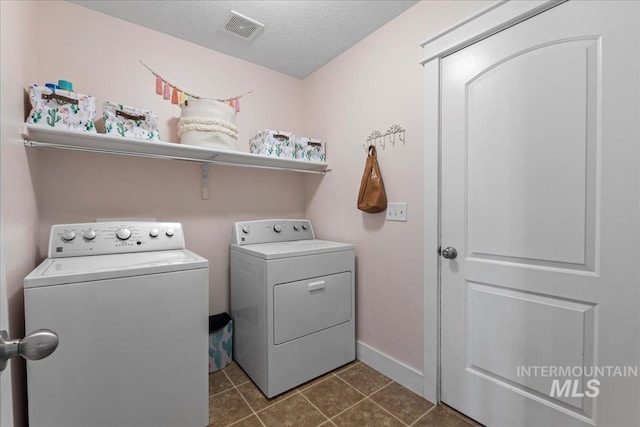 washroom with visible vents, dark tile patterned floors, a textured ceiling, separate washer and dryer, and laundry area