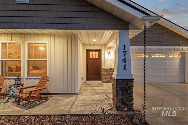 exterior entry at dusk with a garage and concrete driveway