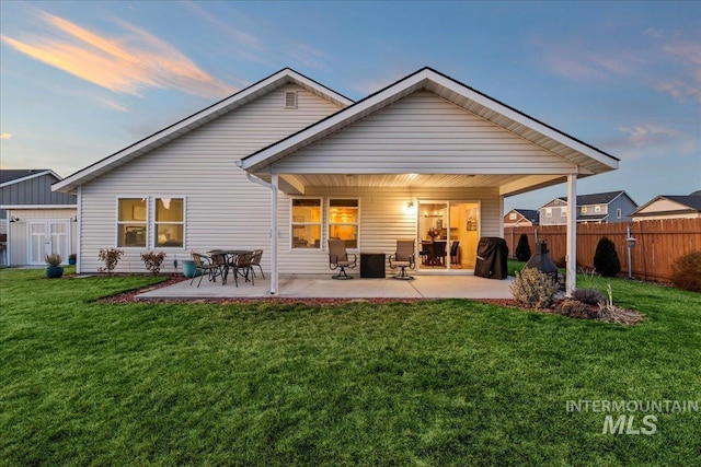 rear view of property with a patio, an outbuilding, fence, a storage unit, and a lawn