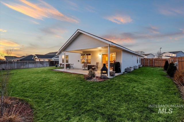 rear view of property featuring a yard, a fenced backyard, and a patio area