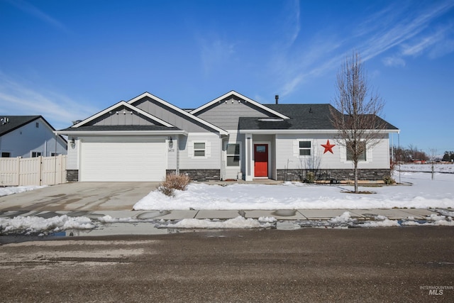 view of front of property with board and batten siding, fence, a garage, stone siding, and driveway