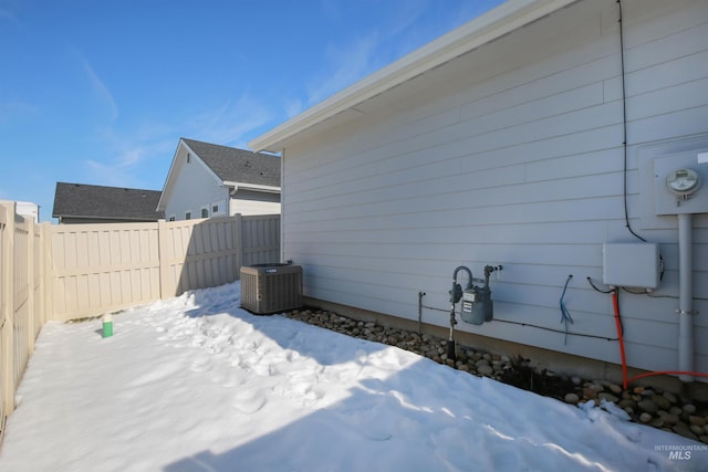 view of snow covered exterior with central air condition unit and a fenced backyard