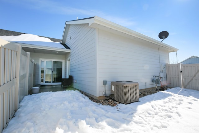 view of snow covered exterior featuring fence, a gate, and central air condition unit