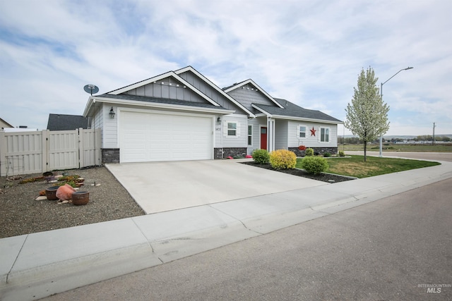 view of front of house featuring fence, stone siding, a gate, an attached garage, and concrete driveway