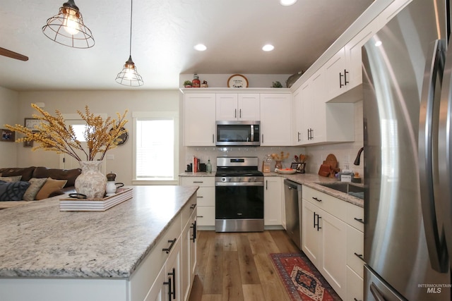 kitchen featuring white cabinetry, stainless steel appliances, dark wood-type flooring, and pendant lighting