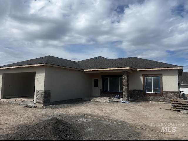 view of front of property featuring stone siding, a garage, and stucco siding