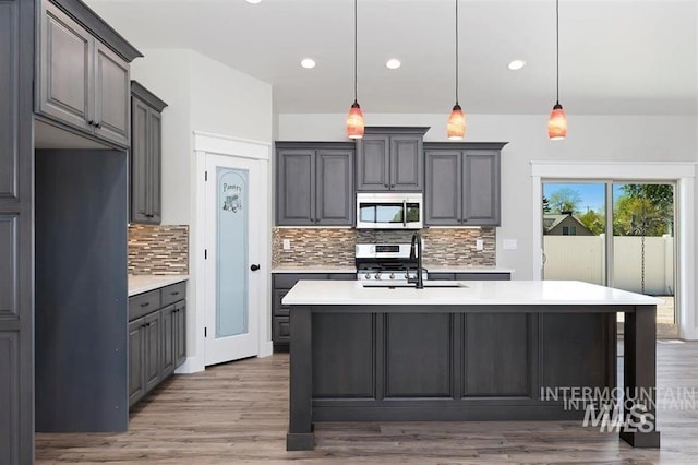 kitchen featuring a sink, light countertops, decorative backsplash, and stainless steel appliances