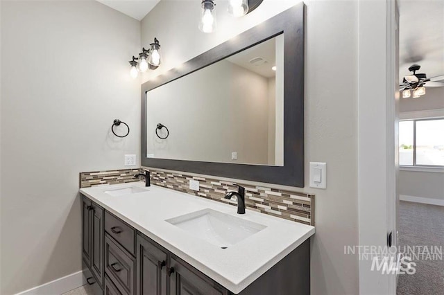 full bath featuring a sink, backsplash, baseboards, and double vanity